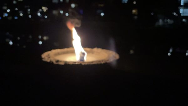Eine Kerze brennt nachts vor einer Stadt.