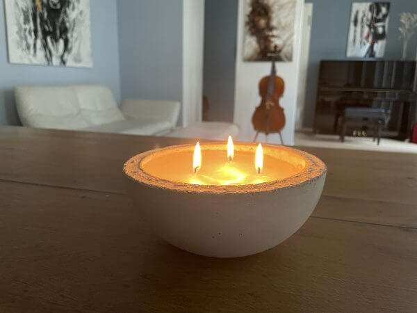 Eine Kerze steht auf einem Holztisch im Wohnzimmer.