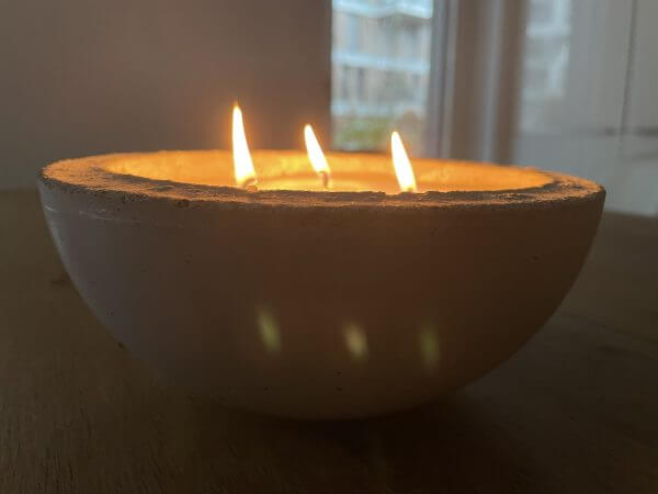Brennende 3-Docht Beton-Kerzen auf einem Holztisch.