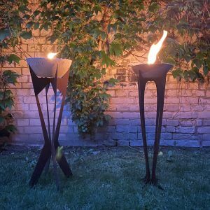 Zwei-brennende-Outdoor-Kerzen-Spreefeuer-Flamelik-und-Kantex-auf-Stahlgestell-in-Edelrost-Optik-Abendstimmung
