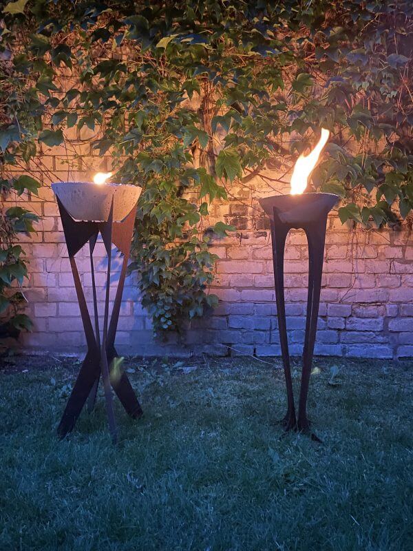Zwei-brennende-Outdoor-Kerzen-Spreefeuer-Flamelik-und-Kantex-auf-Stahlgestell-in-Edelrost-Optik-Abendstimmung